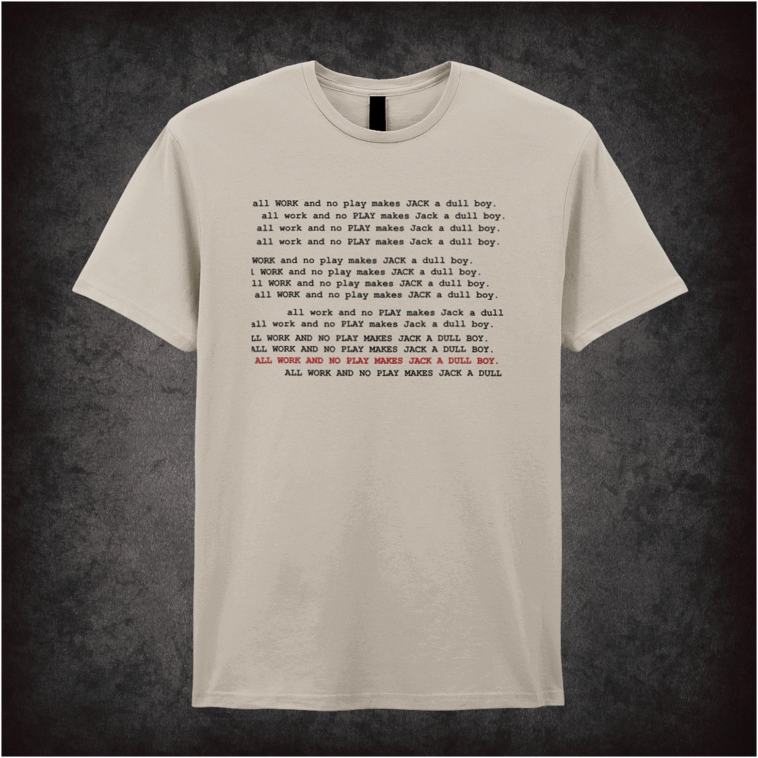 natural unisex t-shirt featuring the phrase “All Work And No Play Makes Jack A Dull Boy” inspired by the movie The Shining, displayed in bold, black typewriter-style lettering.