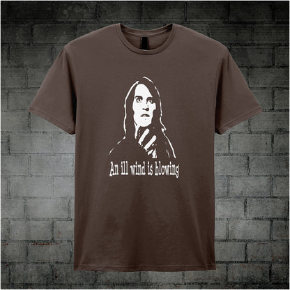 chocolate unisex T-shirt featuring the phrase “An Ill Wind Is Blowing” inspired by The IT Crowd, displayed in bold white text with a dramatic, minimalist design.