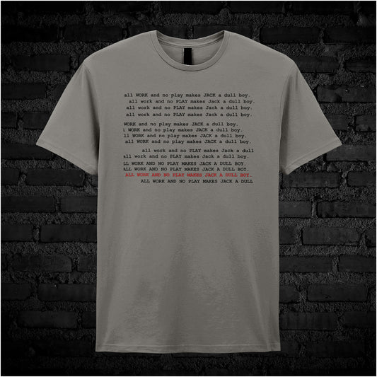 Charcoal unisex t-shirt featuring the phrase “All Work And No Play Makes Jack A Dull Boy” inspired by the movie The Shining, displayed in bold, black typewriter-style lettering.
