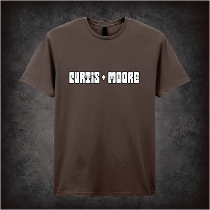 chocolate soft style unisex T-shirt featuring a stylish Curtis and Moore design inspired by The Persuaders!, with bold retro 70s-inspired graphics.