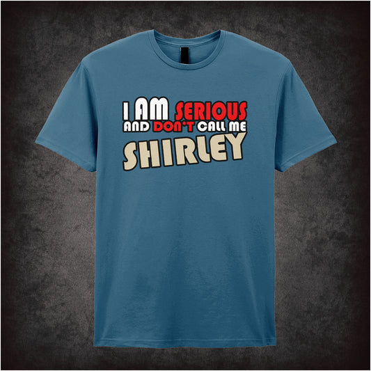 indigo unisex t-shirt featuring the phrase “I Am Serious And Don’t Call Me Shirley” from the movie Airplane!, displayed in bold white red and cream lettering.