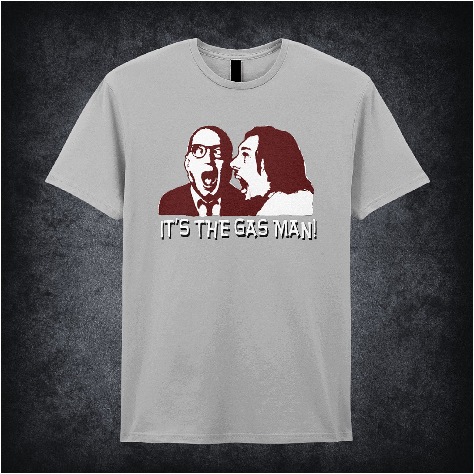 sand unisex T-shirt featuring the phrase “It's The Gas Man!” inspired by Bottom, displayed in bold white lettering with a comedic, punchy style.