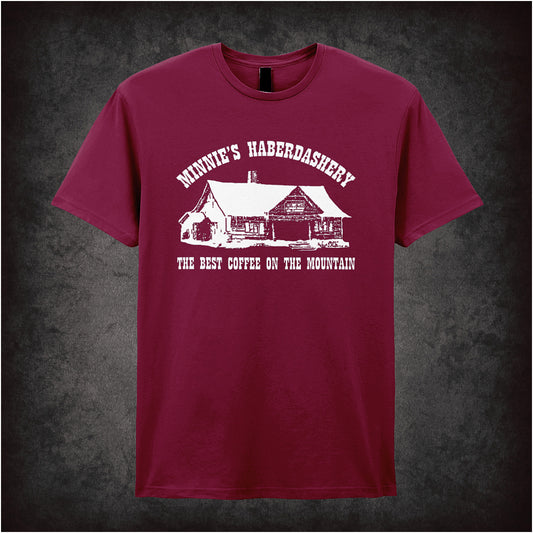Cardinal red unisex t-shirt featuring a design with the text "Minnie's Haberdashery – The Best Coffee On The Mountain," inspired by The Hateful Eight, in vintage western-style lettering.