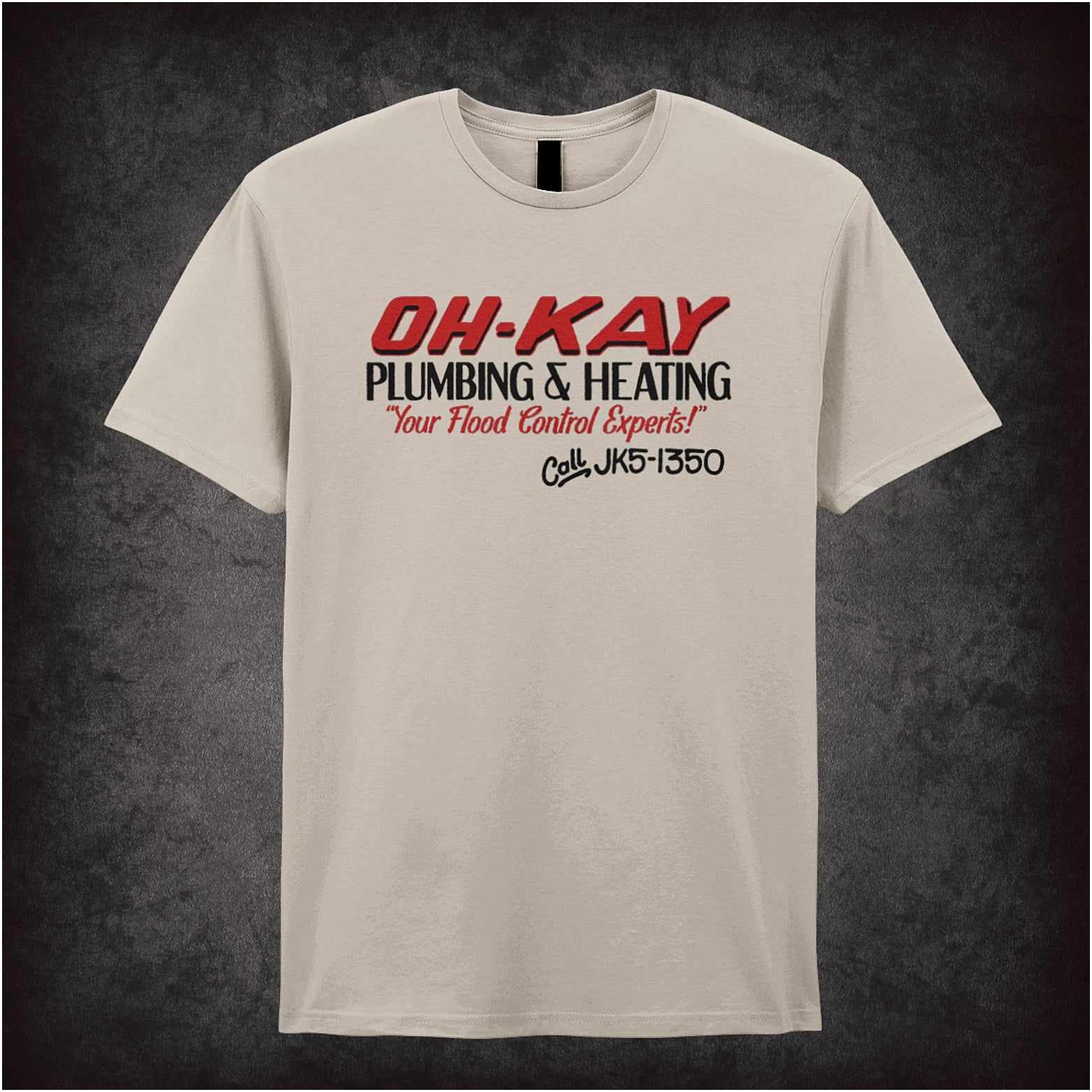 Oh-Kay Plumbing and Heating Home Alone inspired soft style unisex sand coloured T-shirt featuring retro movie design, perfect for fans of the classic holiday film.