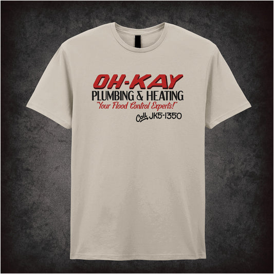 Oh-Kay Plumbing and Heating Home Alone inspired soft style unisex sand coloured T-shirt featuring retro movie design, perfect for fans of the classic holiday film.